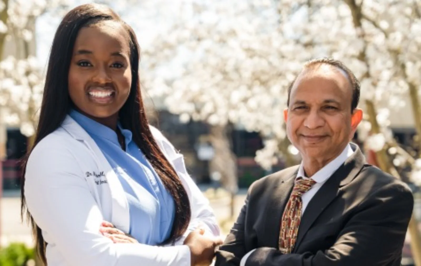 The doctors of MG Dental Associates standing together outdoors in front of flowering trees