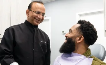 Dr. Mohinder Garg smiling with a patient in the dental chair at MG Dental Associates
